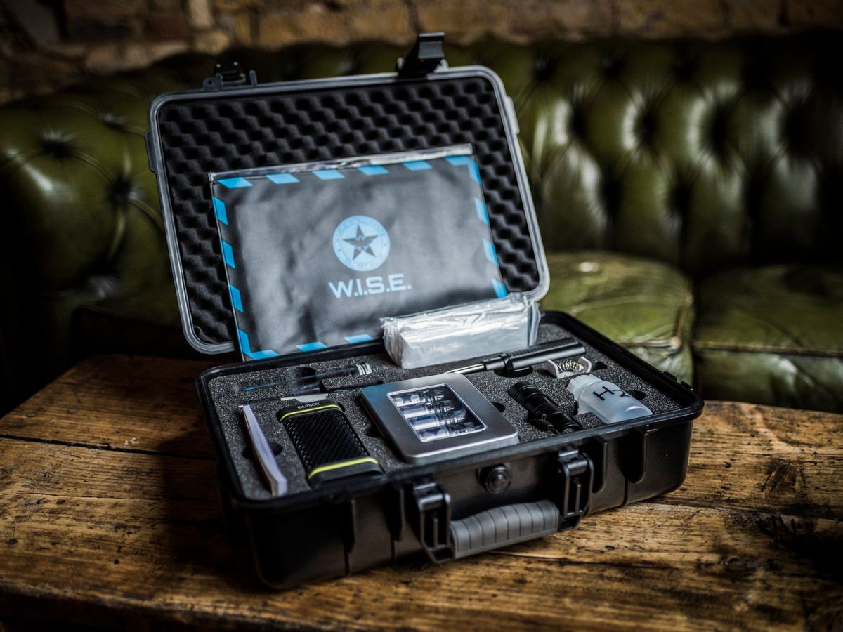 Mallette d'agent ouverte avec gadgets, lampe UV et matériel d'énigmes pour l'escape game