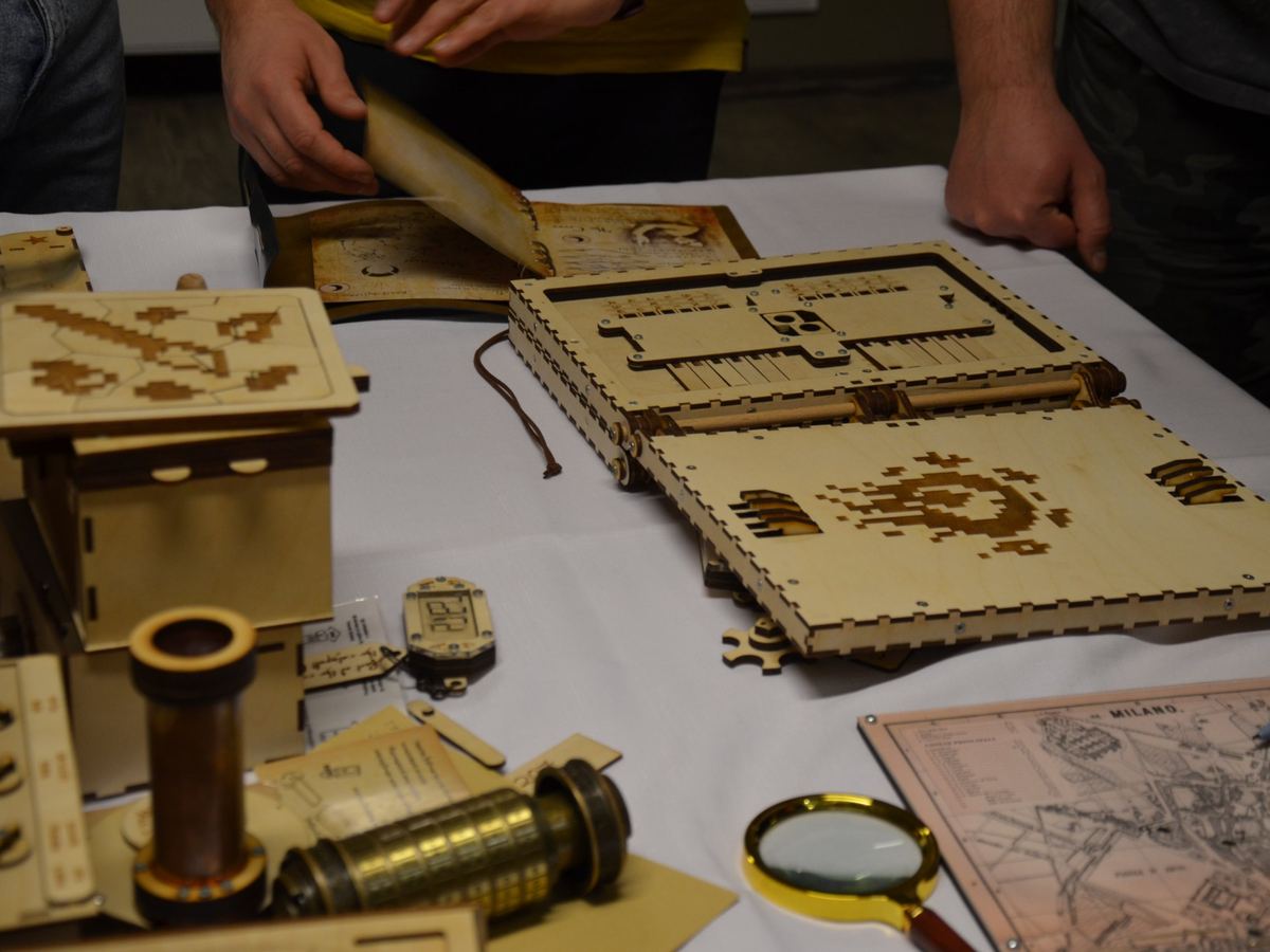 Coffres à énigmes en bois, cryptex et loupe de la Challengebox sur la table de jeu