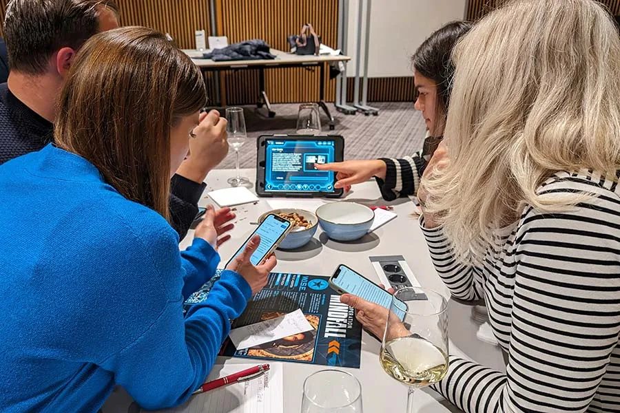 Mitarbeitende spielen ein Indoor Escape Game mit Tablet und Smartphone