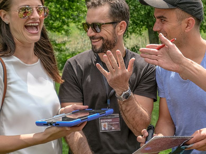 Lachendes Team mit Tablet und Notizen während eines Escape Games im Freien