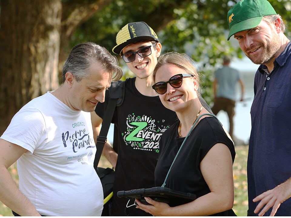 Gut gelauntes Firmenteam mit Tablet unterwegs beim Outdoor Escape Game