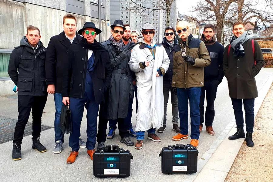Firmenteam mit Agentenkoffern vor dem Start eines Outdoor Escape Games