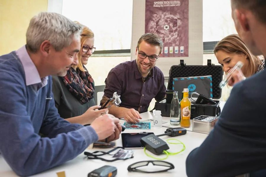Firmenteam untersucht Gadgets und Hinweise am Tisch