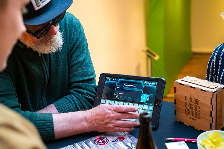 Teilnehmer meldet sein Team auf dem iPad an, daneben die Rätselbox